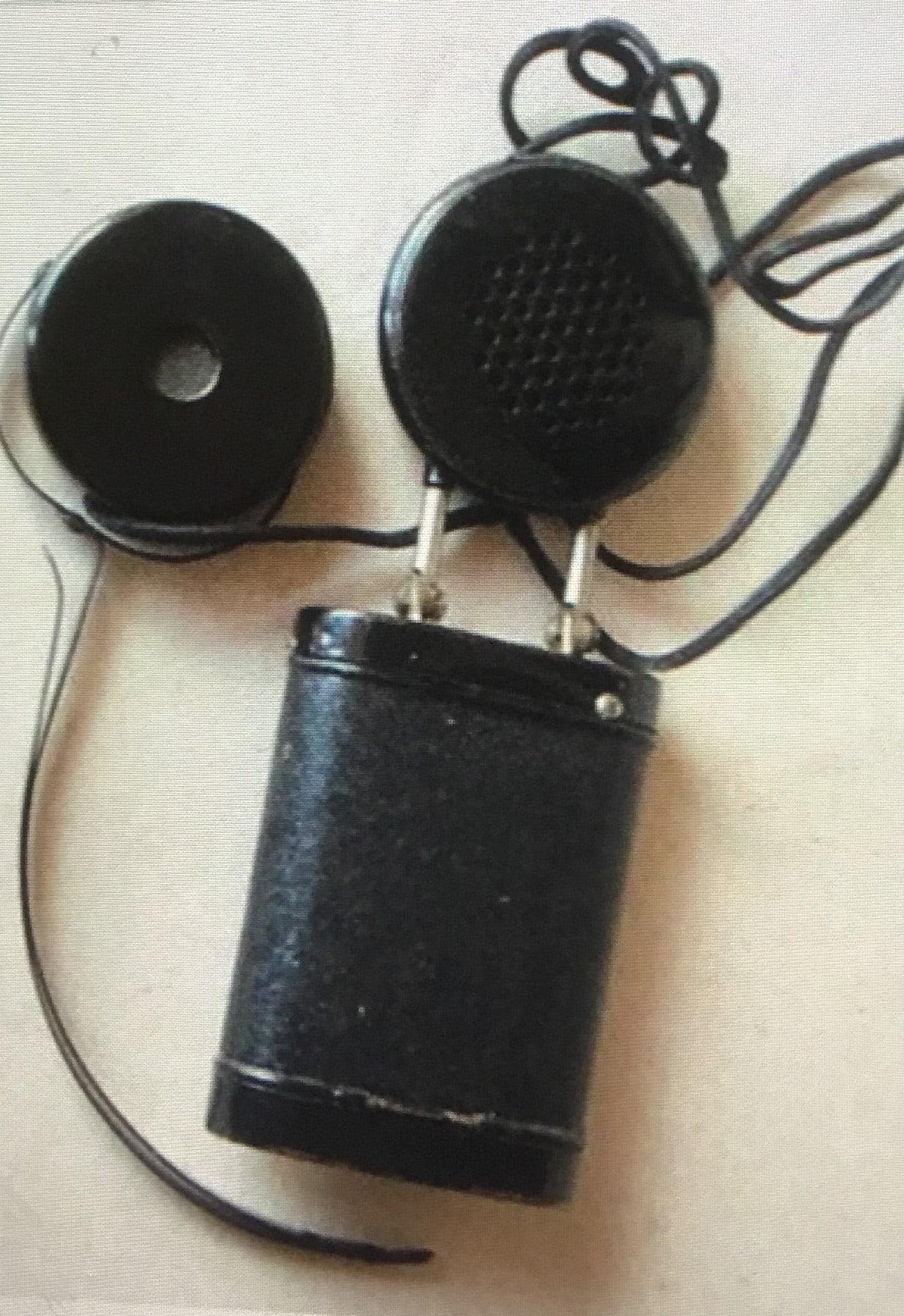A hearing aid from 1930 - round earpiece connected by wires to a round receiver on a square battery