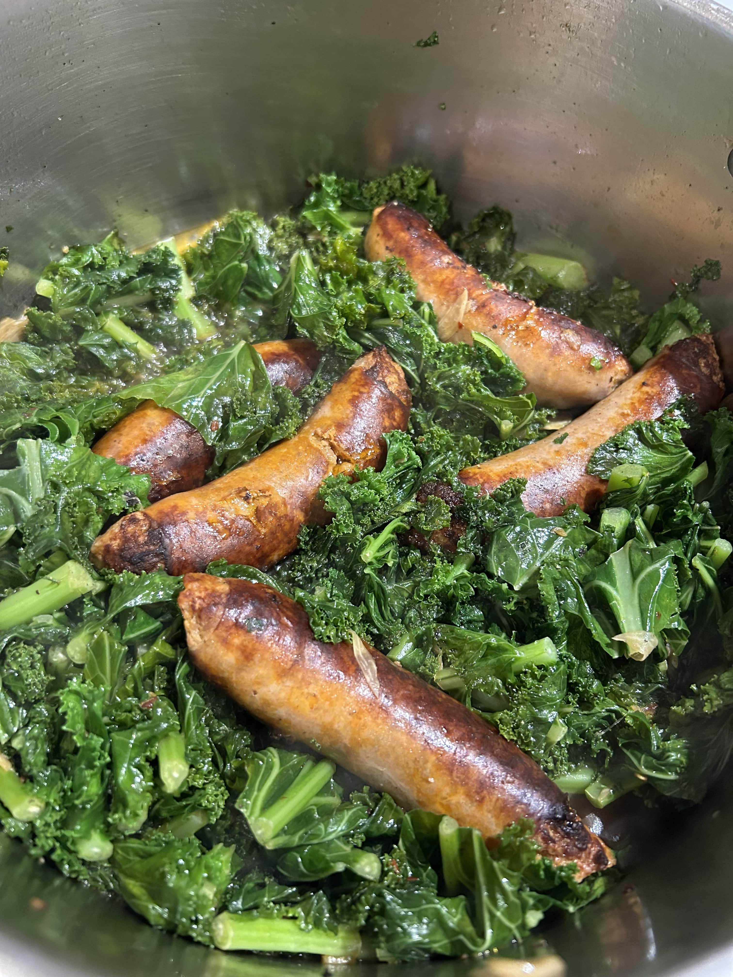 browned sausage links in a bed of bright green chopped kale