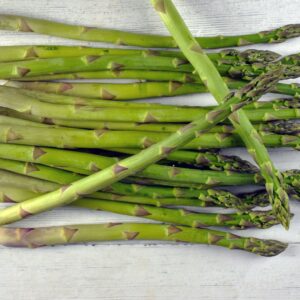 A vibrant bunch of green asparagus spears laid out on a white wooden surface, showcasing fresh produce.