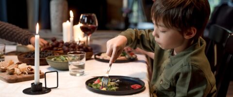 A young boy dining with family at a cozy indoor dinner setting.